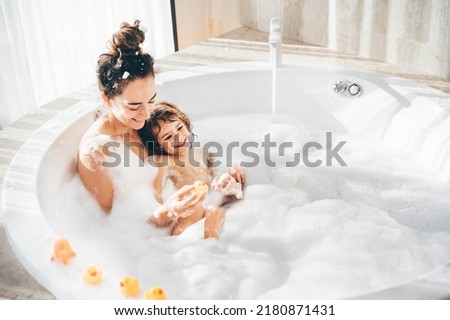 Mother and child having bubble bath.  Royalty-Free Stock Photo #2180871431