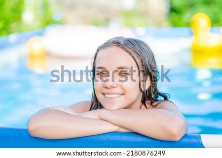 Smiling teen girl enjoying in the pool at sunny day