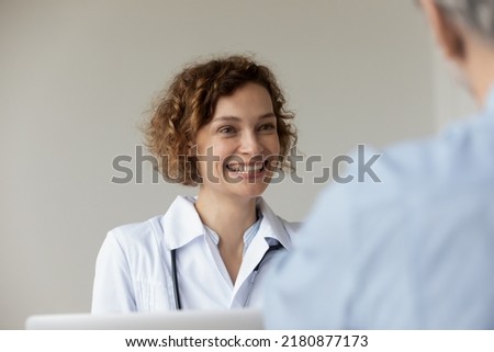 Head shot happy young pretty female general practitioner doctor in white coat looking at patient, sharing good illness treatment news or feeling satisfied with health condition at appointment meeting. Royalty-Free Stock Photo #2180877173