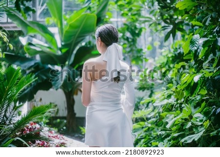 a girl in a white dress is walking in the middle of an exotic garden
