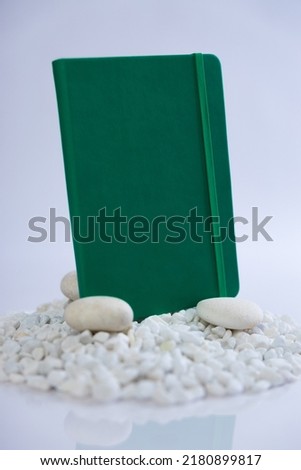 Green notebook on a mountain stack of white rocks. Beautiful studio product photoshoot. High quality photo