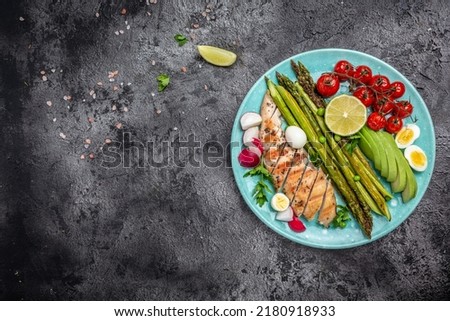 Healthy brunch breakfast with baked asparagus, chicken fillet, cherry tomatoes, avocado, quail eggs and radishes light background. Top view