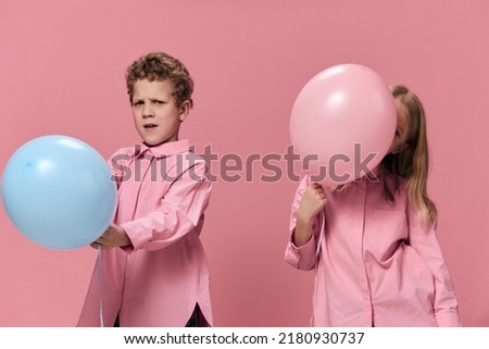 cute happy kids in pink clothes on a pink background have fun playing with colored balloons enjoying childhood