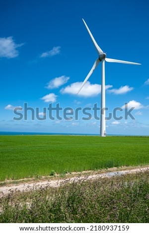 View on modern wind mills, green grain fields and blue Atlantic ocean in agricultural region Pays de Caux in Normandy, France in summer Royalty-Free Stock Photo #2180937159