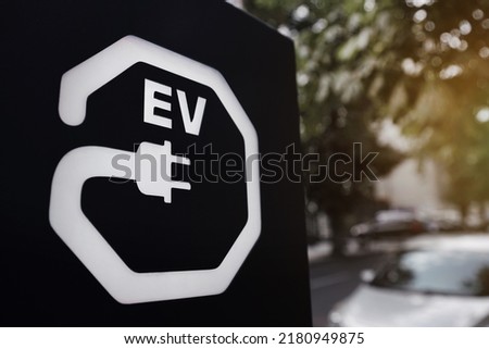 Ev sign with plug icon on black signboard at city street. Vehicle recharge point close up.