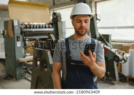 Management team, engineer, or foreman. Standing checking job information about industrial production management within the factory by phone. Teamwork concept.