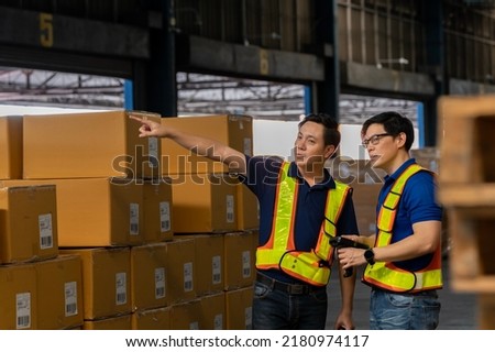 A man in charge of a large warehouse is checking the number of items in the warehouse that he is responsible for. checking goods in a warehouse by scanning a barcode.
