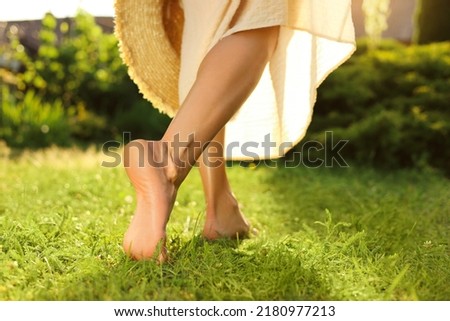 Woman walking barefoot on green grass outdoors, closeup Royalty-Free Stock Photo #2180977213