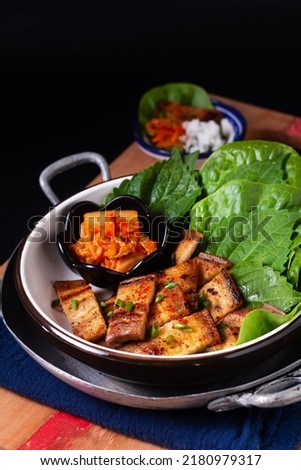 Asian food concept homemade Korean Grilled pork belly BBQ Samgyeopsal-gui with kimchi and shiso and salad on black background with copy space Royalty-Free Stock Photo #2180979317