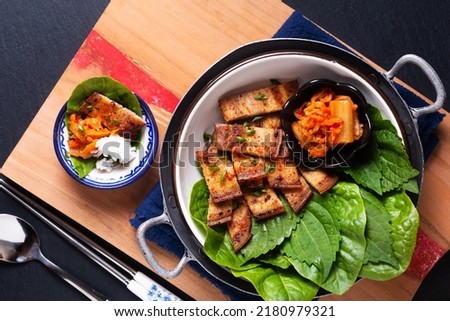 Asian food concept homemade Korean Grilled pork belly BBQ Samgyeopsal-gui with kimchi and shiso and salad on black background with copy space Royalty-Free Stock Photo #2180979321