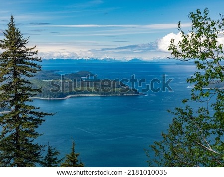View through trees of the bay and mountains at Icy Strait Point near Hoonah in Alaska Royalty-Free Stock Photo #2181010035