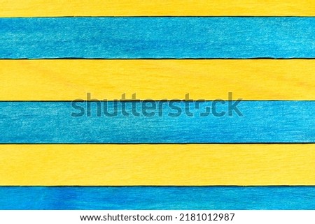 Blue and yellow painted wooden boards. Bright wooden textured background. A wall of alternating blue and yellow wooden planks arranged horizontally.