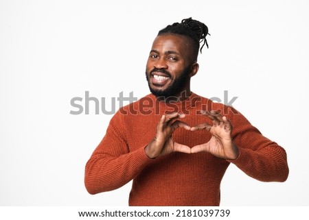 Happy african-american young man with dreadlocks in red sweater showing heart-shape gesture for love passion care isolated in white background
