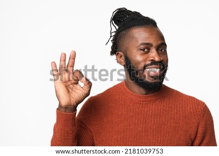 Happy smiling african-american young man with dreadlocks wearing red sweater showing okay gesture isolated in white background