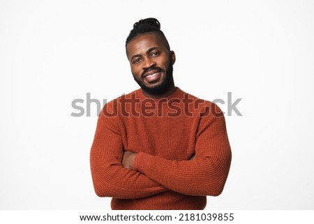 Smiling african-american young man in red sweater with dreadlocks looking at camera with arms crossed isolated in white background