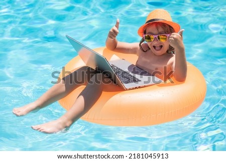 Child sitting in swimming ring in pool and using laptop. Shopping online, freelance concept. Summer travel and business concept.