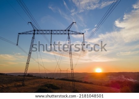 Dark silhouette of high voltage tower with electric power lines at sunrise. Transmission of electric energy concept