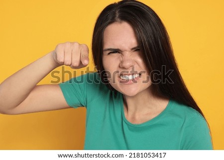 Aggressive young woman pointing on orange background