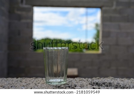 A drinking glass on the window table of a new building.