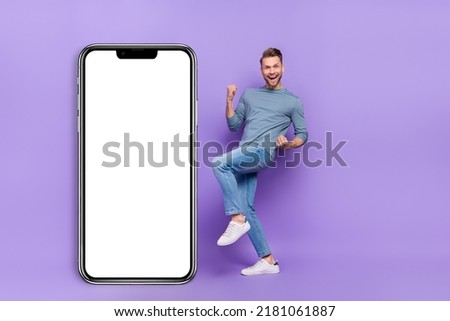 Photo of cheerful lucky guy wear grey shirt modern device empty space rising fists isolated violet color background