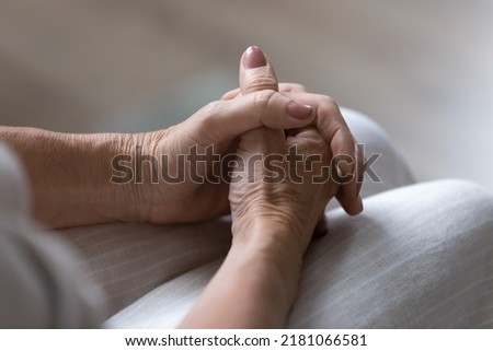 Clasped hands on lap of nervous anxious mature 60s lady waiting for important news. Senior 70s woman keeping wrists and palms in worried position. Anxiety, body gesture concept. Close up Royalty-Free Stock Photo #2181066581