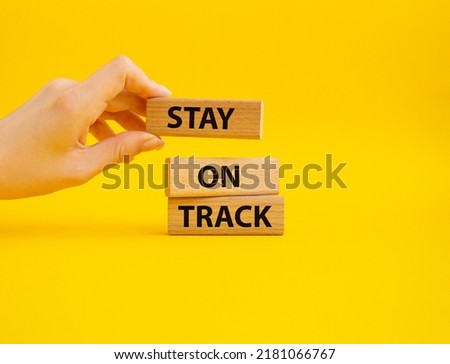 Stay on track symbol. Wooden blocks with words Stay on track. Beautiful yellow background. Businessman hand. Business and Stay on track concept. Copy space.