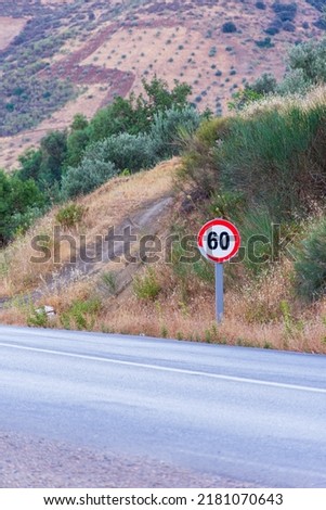 View of a traffic sign with a speed limit of 60 kilometers per hour on a countryside road.