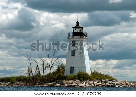 Sun breaks through storm clouds at old tower of Black Rock Harbor lighthouse, also known as Fayerweather Island light, in Bridgeport, Connecticut. Royalty-Free Stock Photo #2181076739