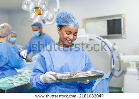 Portrait of female woman nurse surgeon OR staff member dressed in surgical scrubs gown mask and hair net in hospital operating room theater making eye contact smiling pleased happy looking at camera Royalty-Free Stock Photo #2181082049