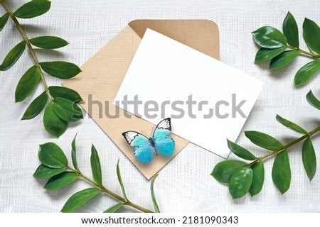 Mock up card with plants and blue butterfly. Invitation card with envelope on white background