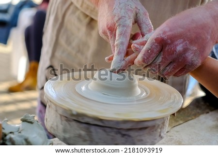 Close up of human hands. An expert potter teaching child pottery. The artisan creates works of art with his hands. Concept of: experience, art, tradition, clay