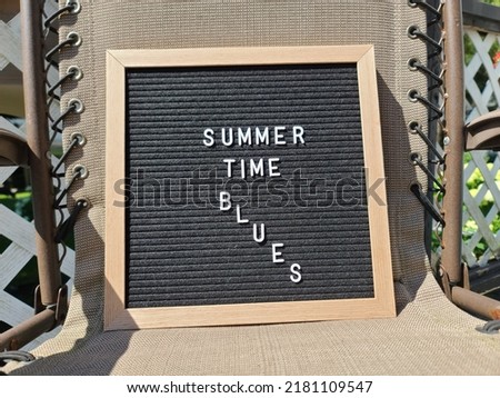 A sign saying summer time blues. The felt sign has removable letters than can be moved around to make whatever words or saying one wants. 