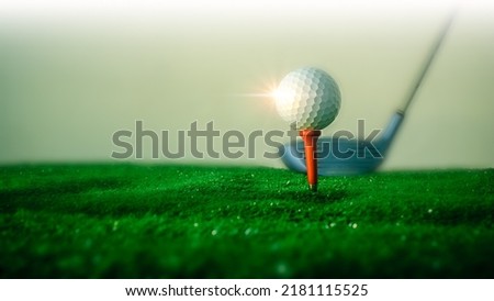 Close-up of a golf ball on the hitting platform Golf ball on red platform on green grass and golf club in the back ready to hit.Sports and health concept