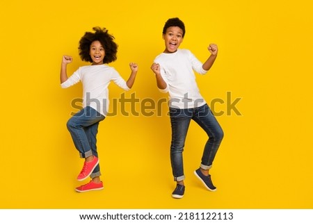 Photo of funky lucky schoolboy schoolgirl wear white shirt rising fists isolated yellow color background Royalty-Free Stock Photo #2181122113
