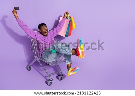 Full size photo of amazed funny guy hold packages debit card look empty space isolate don purple color background