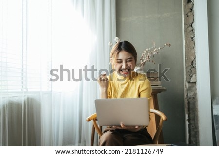 Young woman with laptop expressing excitement in home office, Excited Asian woman feel euphoric reading good news online.