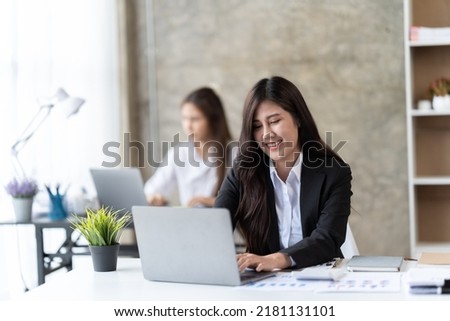 beautiful focused woman working with laptop while sitting at table in office, 