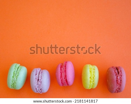 Delicious colorful Macarons almond cookies diffrent colors and flavor on bright orange background. Top view flat lay food photography. Mockup, free copy space for text, border, vertical or horizontal