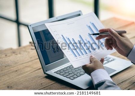 Businessman holding documents containing financial statistics, stock photos, discussion and data analysis, charts and graphs, charts, diagrams, business, and work concepts.