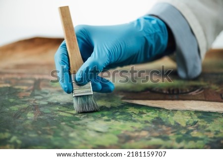 Restoring old oil painting, conservator removing varnish from an oil painting Royalty-Free Stock Photo #2181159707