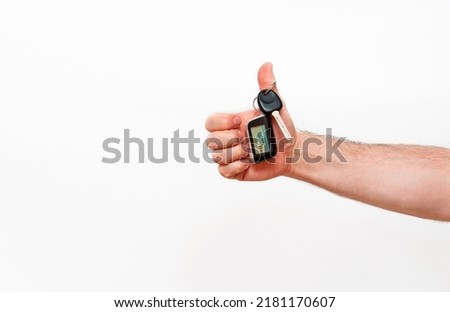 A man hand holds a car key with an alarm keychain isolated on white.  The concept of a new car