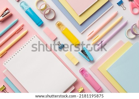 Back to school concept. Top view photo of colorful stationery copybooks pens staplers binder clips correctors erasers and adhesive tape on bicolor white and pink background with blank space Royalty-Free Stock Photo #2181195875