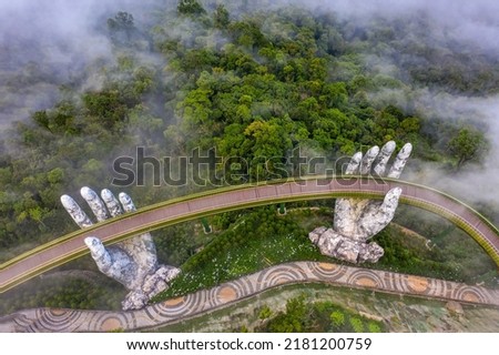 Aerial view of the Golden Bridge is lifted by two giant hands in the tourist resort on Ba Na Hill in Da Nang, Vietnam. Ba Na mountain resort is a favorite destination for tourists Royalty-Free Stock Photo #2181200759