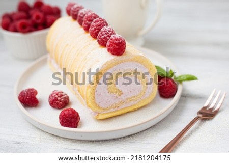 Tasty roll cake, sponge roll, Swiss roll  stuffed with cream cheese ,decorated with fresh raspberries.  Royalty-Free Stock Photo #2181204175
