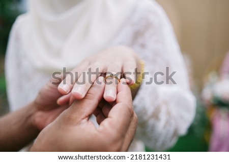 close up hand muslim groom waering wedding ring to left finger of muslim bridge with copy space.concept for wedding card background,poster, invitation card  Royalty-Free Stock Photo #2181231431