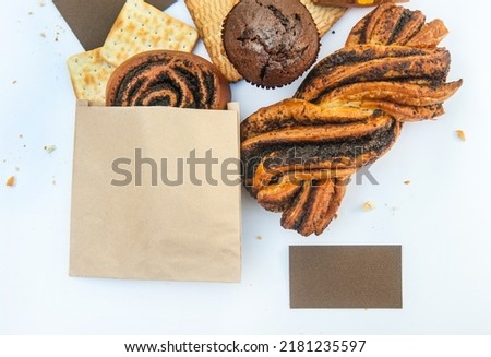 Bright pastries on a white backdrop, flat lay template with empty business card and paper bakery pocket