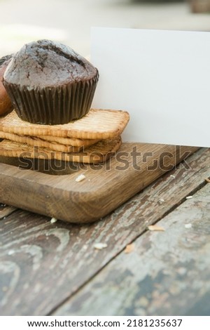 Chocolate cupcake and cookies with empty business card mockup, outdoor photo