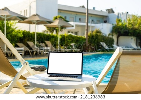 A laptop with an empty screen stands in the courtyard of a beautiful home garden, in Sunny weather.
