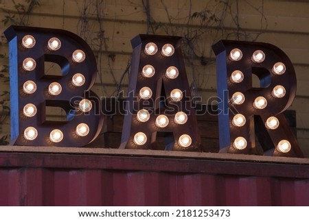 The word BAR made up of Edison light bulbs. Vintage sign made with metal letters with lamps. Bar, cafe or restaurant electric sign in retro style.