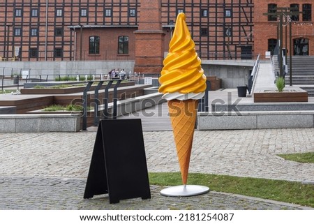 Large ice cream plastic figure near the ice cream cafe in the park. Blank restaurant shop sign or menu board. Cafe menu on the street. Blackboard sign mockup in front of a restaurant.